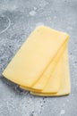 Uncooked Raclette Swiss cheese slices. Gray background. Top view