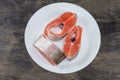 Uncooked rainbow trout pieces on white dish on black surface Royalty Free Stock Photo