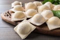 Uncooked ravioli, basil and peppercorns on wooden table, closeup