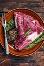 Uncooked Raw goat thigh or leg with rosemary and thyme in rustic plate. Dark wooden background. Top view. Copy space Royalty Free Stock Photo