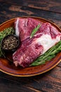 Uncooked Raw goat thigh or leg with rosemary and thyme in rustic plate. Dark wooden background. Top view. Copy space Royalty Free Stock Photo