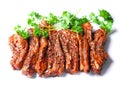 Uncooked raw marinated style pork belly chops on a white background with coriander leafs. Korean style marinade over the slices.