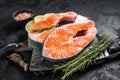 Uncooked Raw Salmon Fish Steaks on butcher board with herbs. Black background. Top view Royalty Free Stock Photo