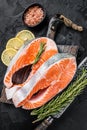 Uncooked Raw Salmon Fish Steaks on butcher board with herbs. Black background. Top view Royalty Free Stock Photo