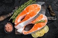 Uncooked Raw Salmon Fish Steaks on butcher board with herbs. Black background. Top view Royalty Free Stock Photo