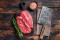 Uncooked Raw Shoulder Top Blade or flat iron beef meat steaks on a wooden butcher board with meat cleaver. Dark wooden Royalty Free Stock Photo