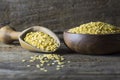 Uncooked raw yellow lentil in wooden shovel and bowl on wooden rustic table Royalty Free Stock Photo