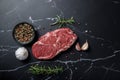 Uncooked rib eye beef steak with rosemary and spices on dark marble Royalty Free Stock Photo