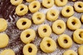 Uncooked round donuts on table with flour before frying