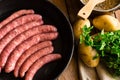 Uncooked sausages in iron cast pan, potatoes and fresh parsley, pot with rice, top view Royalty Free Stock Photo