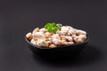 Uncooked sea mussels meat with green parsley in a clay black dish