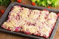 Uncooked slices of meat covered with chopped onion and sprinkled with cheese on a baking sheet