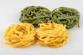 Uncooked tagliatelle pasta, green and yellow, four nests Royalty Free Stock Photo