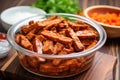 uncooked tempeh ribs marinated in bbq sauce in a clear bowl