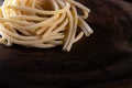 Uncooked traditional hand - rolled durum wheat pasta Pici of Tuscany, wooden rustic background