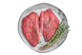 Uncooked Wagyu chuck steaks with deep red texture and thyme garnish set on gray ceramic plate on light backdrop perfect Royalty Free Stock Photo