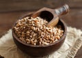 Uncooked whole spelt in a bowl with a wooden spoon Royalty Free Stock Photo