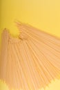 Uncooked yellow long spaghetti on a rustic background. Yellow italian pasta. Long spaghetti