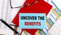 UNCOVER THE BENEFITS text on sticky on red notebook on chart background Royalty Free Stock Photo