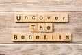 Uncover the benefits word written on wood block. uncover the benefits text on table, concept