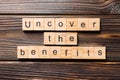 Uncover the benefits word written on wood block. uncover the benefits text on table, concept