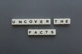 Uncover the facts word made of square letter word on grey background.