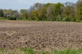 Uncultivated agricultural land, plowed and prepared for planting vegetables surrounded by lush green trees