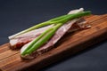 Uncured Apple Smoked Bacon garnished with Green Onion Scallions on natural wooden cutting board Royalty Free Stock Photo