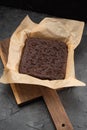 Uncutted brownies with choco drops in baking paper on dark plaster background Royalty Free Stock Photo