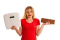 Undecided woman holding scale and chocolate uncertain wether to