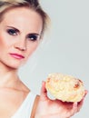 Undecided woman holds cake sweet bun in hand