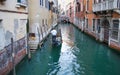 Undefined gondolier operate gondola through the narrow canal of Venice