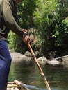 Undefined man drives a makeshift raft sailing along a river in the jungle