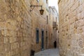 Undefined woman wandering along typical narrow medieval street of Mdina