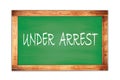 UNDER ARREST text written on green school board