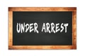 UNDER ARREST text written on wooden frame school blackboard