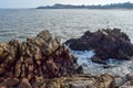 Under the blue sky, the waves beat the rocks on the beach