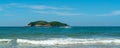 Under the blue sky and white clouds, the waves wash on the beach, and the small island in the distance