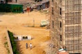 Under construction multi story building with rusted scaffolding and an empty dirt path on the side