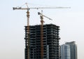 Under construction tall building skyscraper with yellow construction cranes next to it Royalty Free Stock Photo