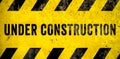 Under construction warning sign text with yellow black stripes painted over concrete wall cement facade texture background banner