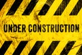 Under construction warning sign text with yellow black stripes painted on wood wall plank texture wide background Royalty Free Stock Photo