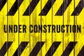 Under construction warning sign text with yellow black stripes painted on wood wall plank texture wide background Royalty Free Stock Photo