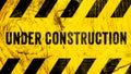 Under construction warning sign text with yellow black stripes painted on wood wall plank texture wide banner panorama background. Royalty Free Stock Photo