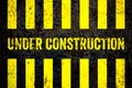 Under construction warning sign with yellow and black stripes painted over cracked concrete wall coarse texture background Royalty Free Stock Photo