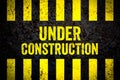 Under construction warning sign with yellow and black stripes painted over cracked concrete wall weathered texture background Royalty Free Stock Photo