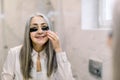 Under eye masks for puffiness, wrinkles, dark circles. Eye patches concept. Reflection in the mirror of smiling senior Royalty Free Stock Photo