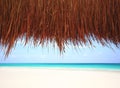 Under a thatched hut at a resort beach Royalty Free Stock Photo