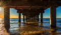 Under the pier at beautiful golden orange sunset