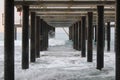 Under pier view. Waves beat about piles.